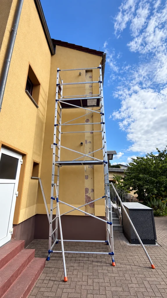 Geöffnete Fassade mit Rollgerüst während der Verlegung von Vor- und Rücklauf, rechts die Ovum AC520P Außeneinheit